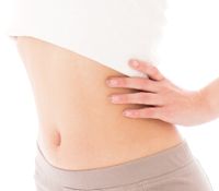 乳酸菌やラクチュロースなどの整腸効果ですっきりとしたお腹の女性